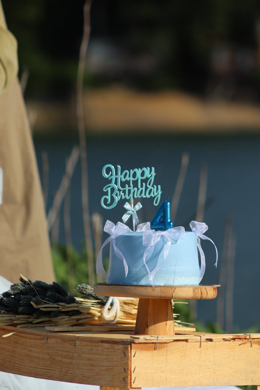 blue birthday cake outdoors near a lake